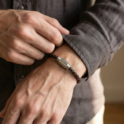 Brown braided leather men’s bracelet with brushed stainless steel clasp worn on wrist in lifestyle setting
