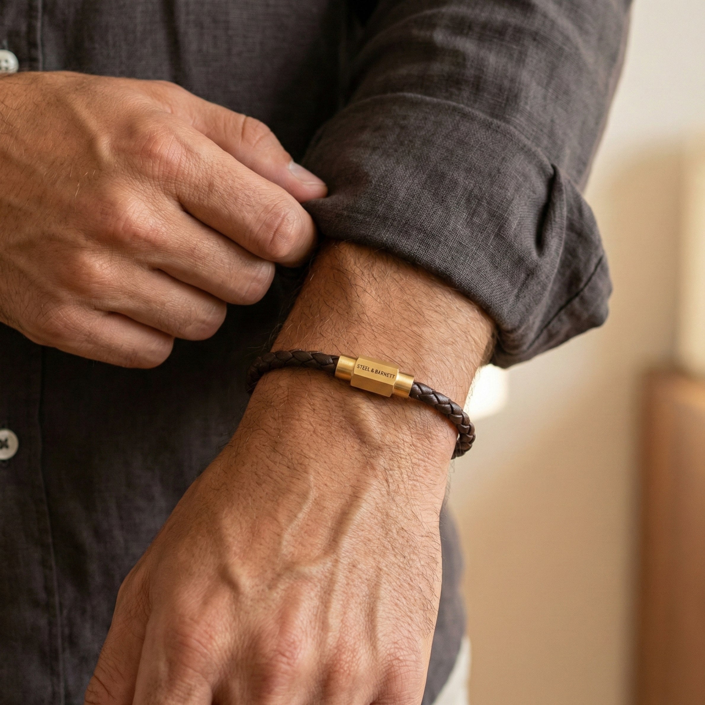 Brown braided leather men’s bracelet with plated 18K gold clasp worn on wrist in close up