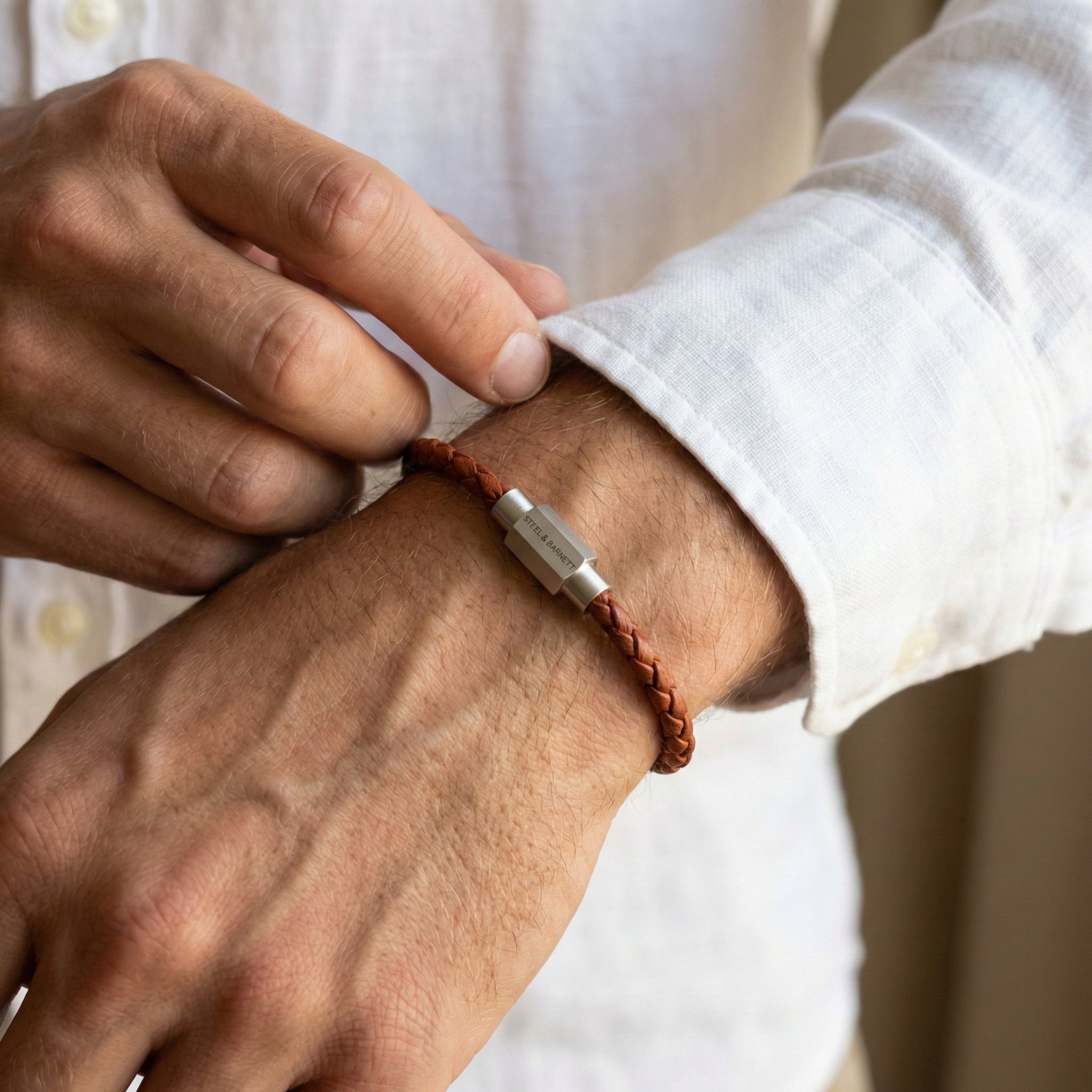 Cognac braided leather men’s bracelet with brushed stainless steel magnetic clasp worn on wrist in close up
