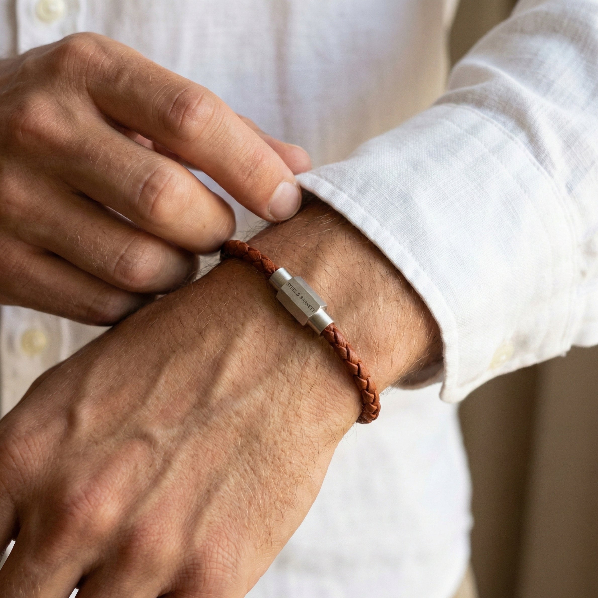 Cognac braided leather men’s bracelet with brushed stainless steel magnetic clasp worn on wrist in close up