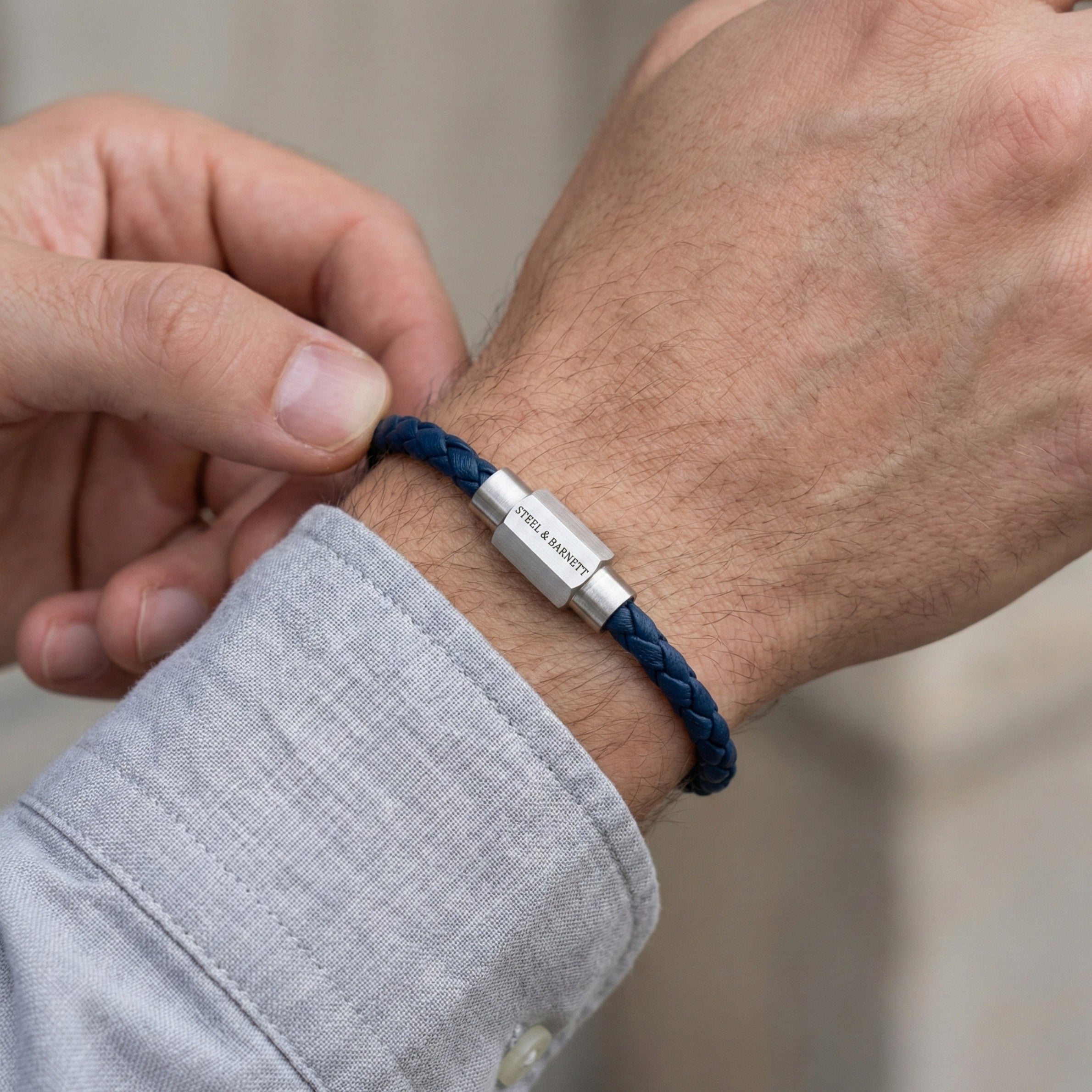 Blue braided leather men’s bracelet with brushed stainless steel magnetic clasp worn on wrist in close up
