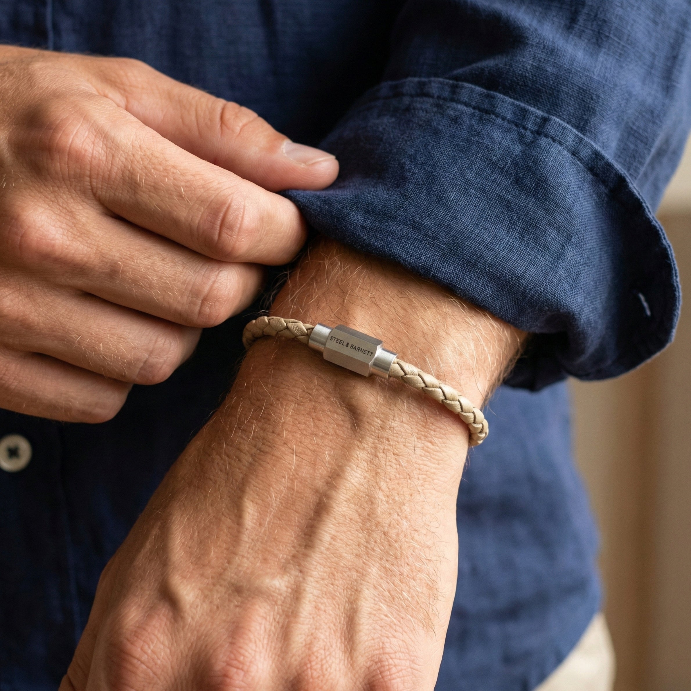 Beige braided leather men’s bracelet with brushed stainless steel magnetic clasp worn on wrist in close up