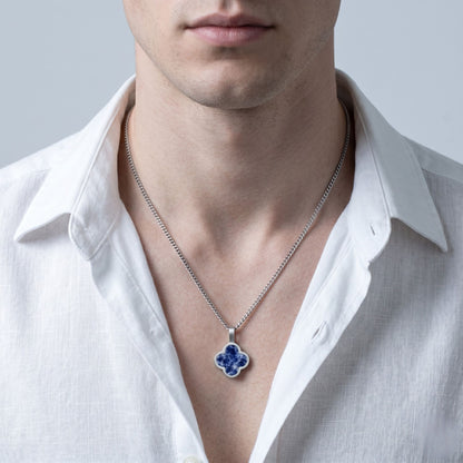 Man wearing a white shirt with a silver necklace featuring a blue sodalite  pendant.