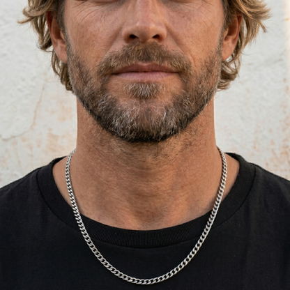 Man wearing a black shirt and silver chain necklace against a neutral background