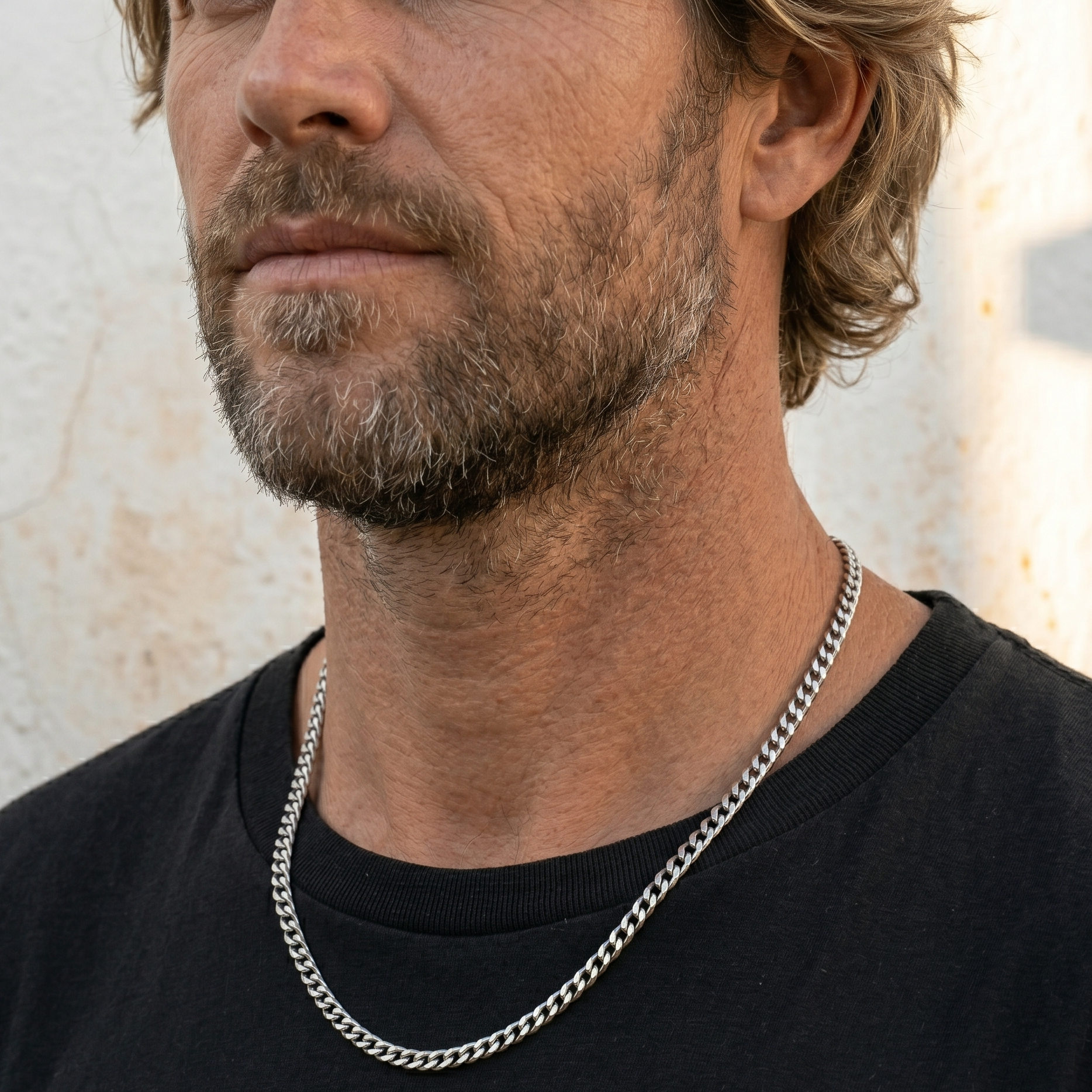 Man wearing a silver chain necklace against a neutral background