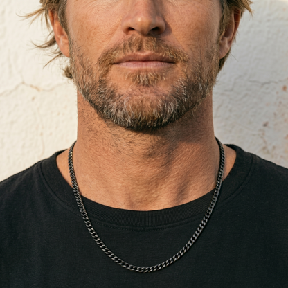 Man wearing a black chain necklace against a neutral background