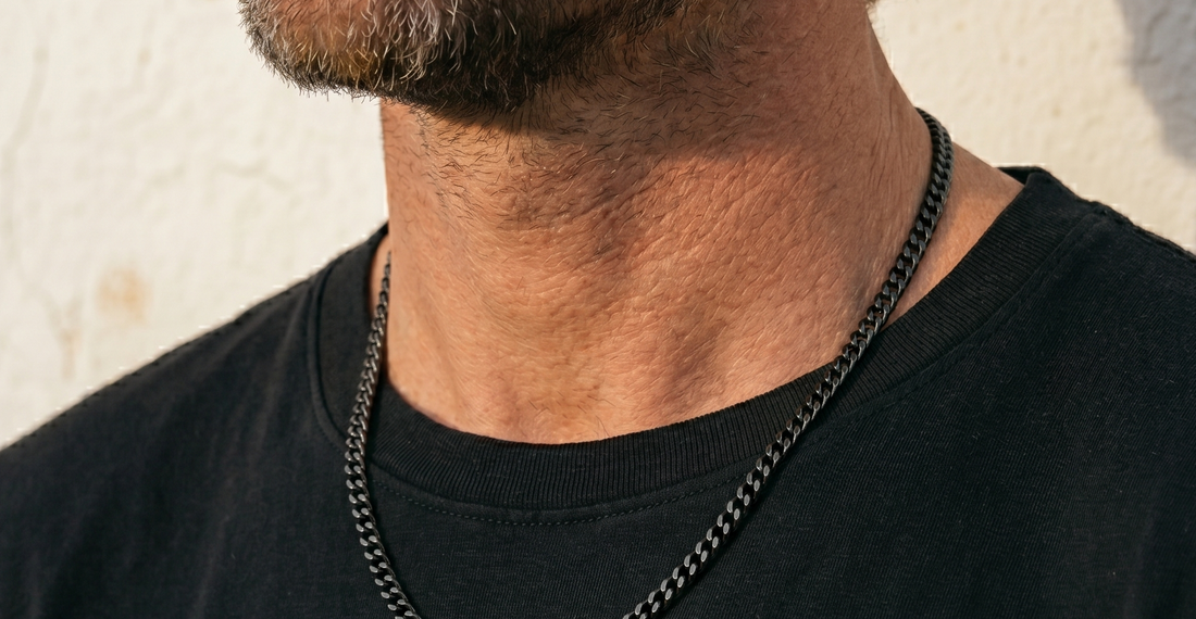 Man wearing a black chain necklace against a light background