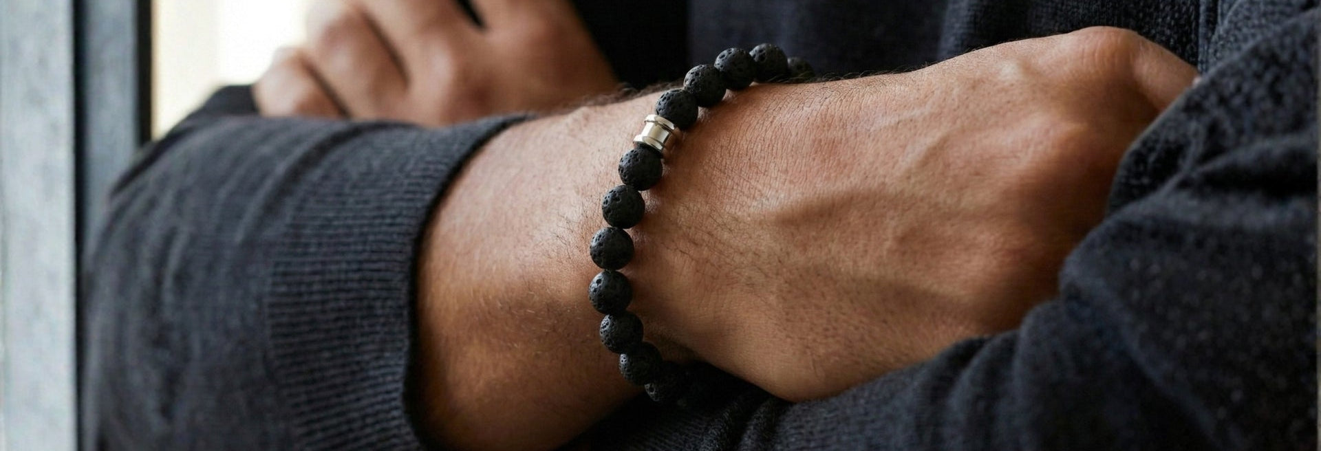 Black beaded men's bracelet with matte stone beads and stainless steel accent detail worn on wrist in a close up indoor shot