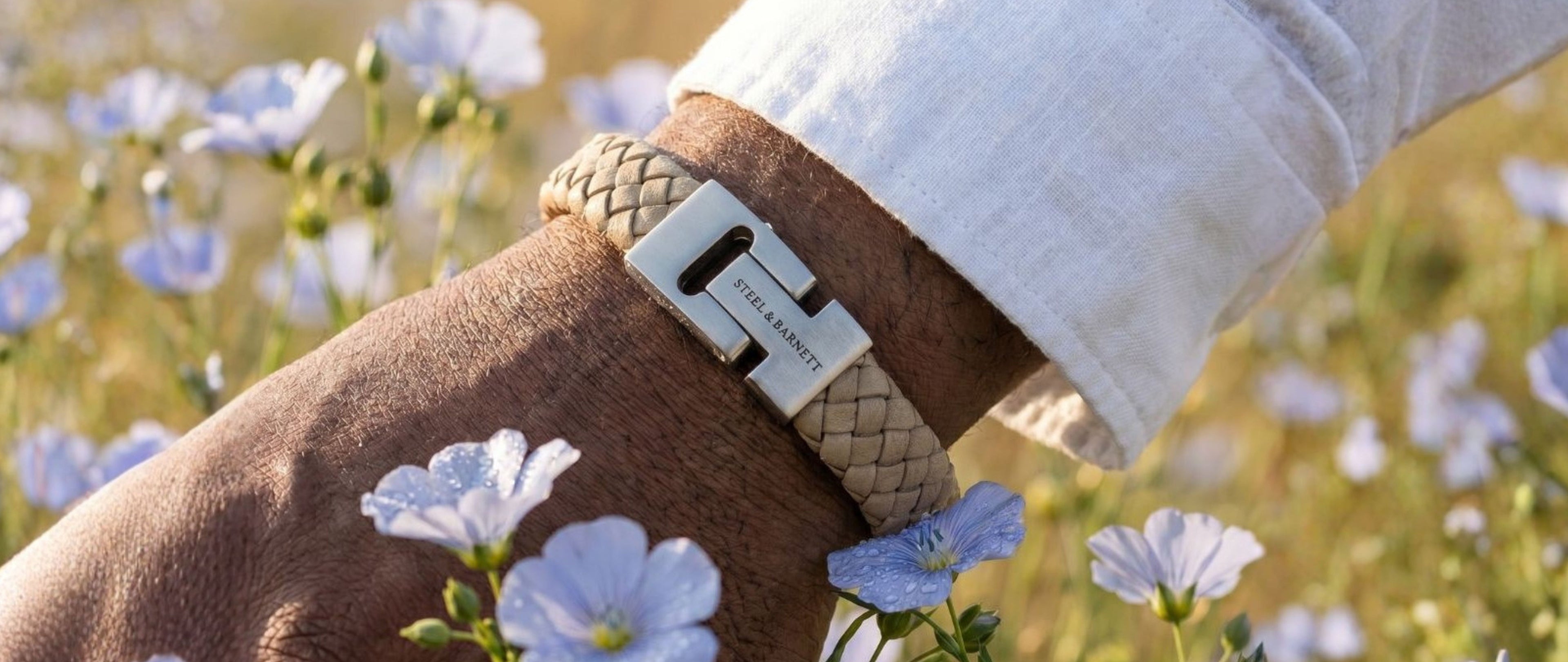 Bracelet with a brand logo worn on a wrist against a floral background