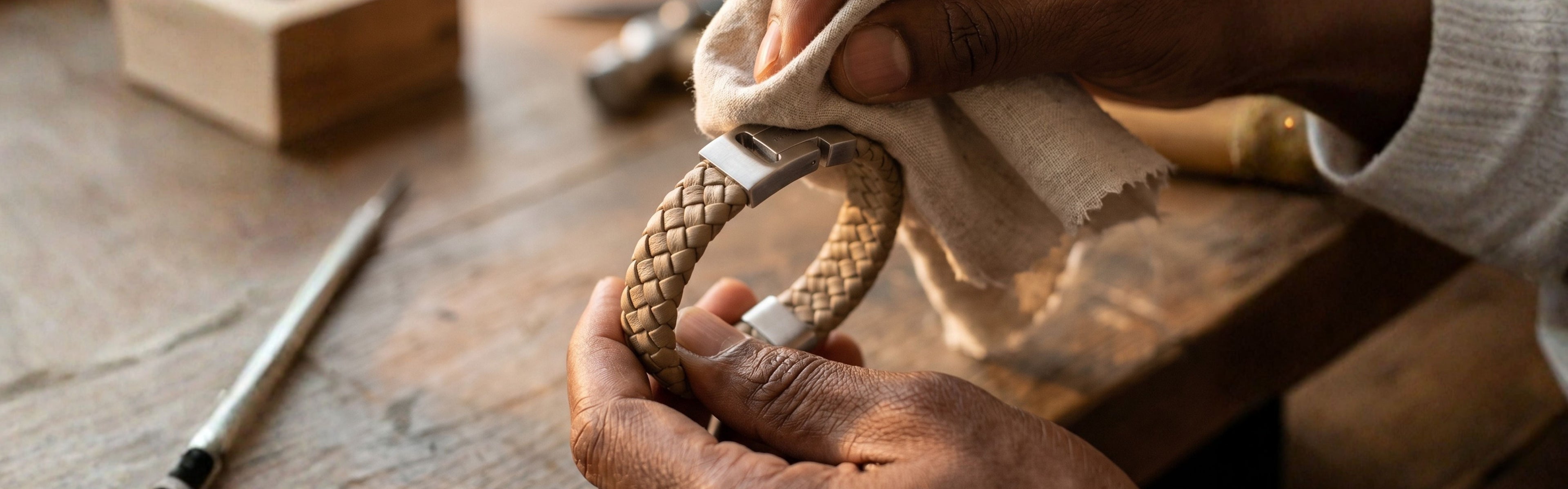 Person cleaning a braided object with a cloth on a wooden table.