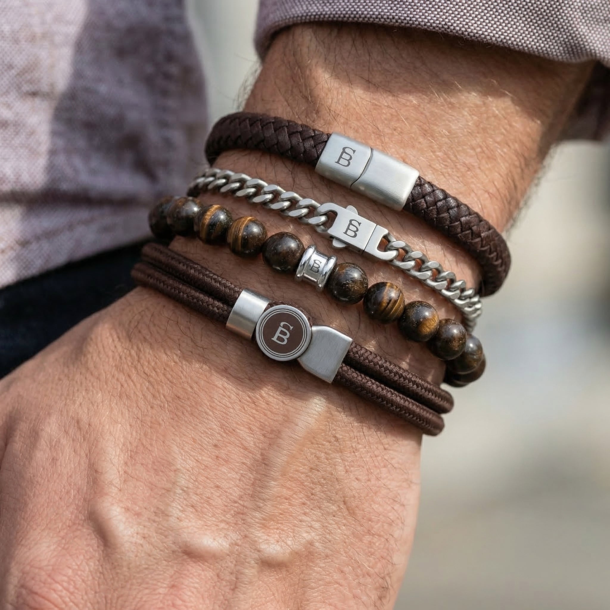 Stacked brown leather cord, braided leather, beaded stone and stainless steel men's bracelet set worn on wrist with mixed textures