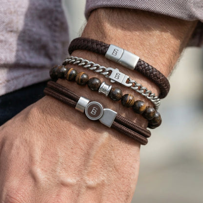 Stacked brown leather cord, braided leather, beaded stone and stainless steel men's bracelet set worn on wrist with mixed textures