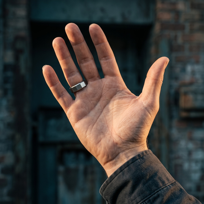 Silver stainless steel men's ring with a brushed geometric finish shown on an open hand in natural outdoor light