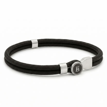 Black rope men’s bracelet with brushed stainless steel magnetic clasp and round logo detail on a white background