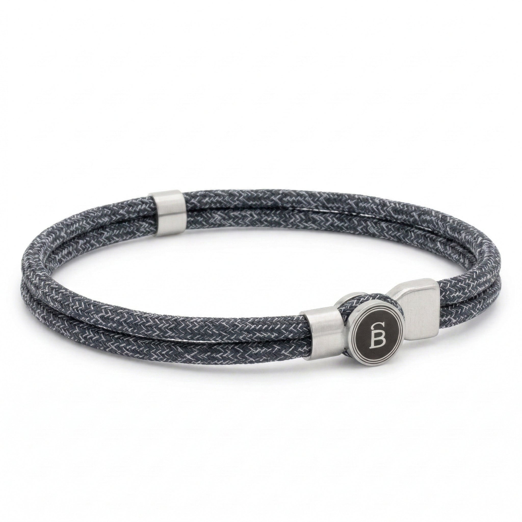 Grey braided rope men’s bracelet with brushed stainless steel magnetic clasp and round logo detail on a white background