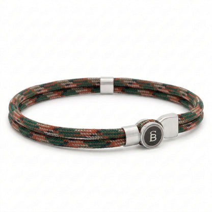 Green and brown patterned rope men’s bracelet with brushed stainless steel magnetic clasp and round logo detail on a white background