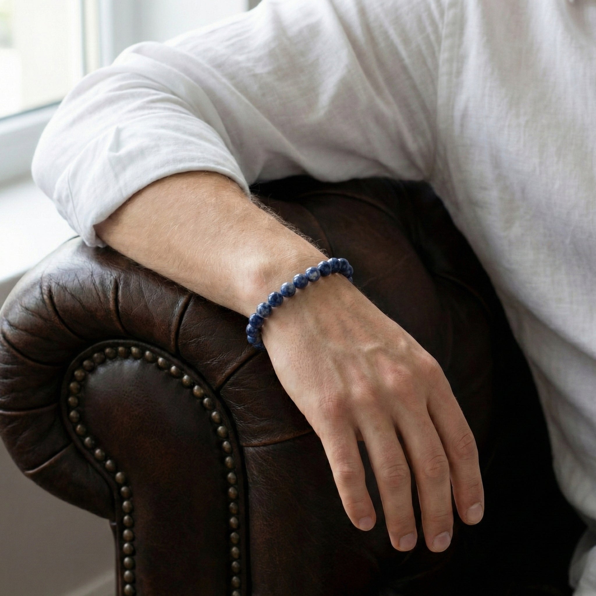 Blue beaded men’s bracelet with polished natural stone beads worn on wrist in a lifestyle setting