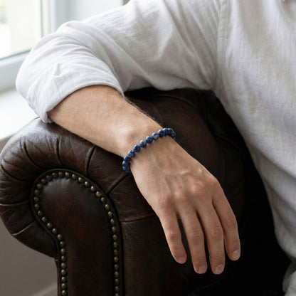 Blue beaded men’s bracelet with polished natural stone beads worn on wrist in a lifestyle setting