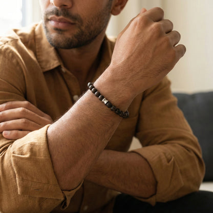 Dark brown beaded men’s bracelet with matte wooden beads and stainless steel detail worn on wrist