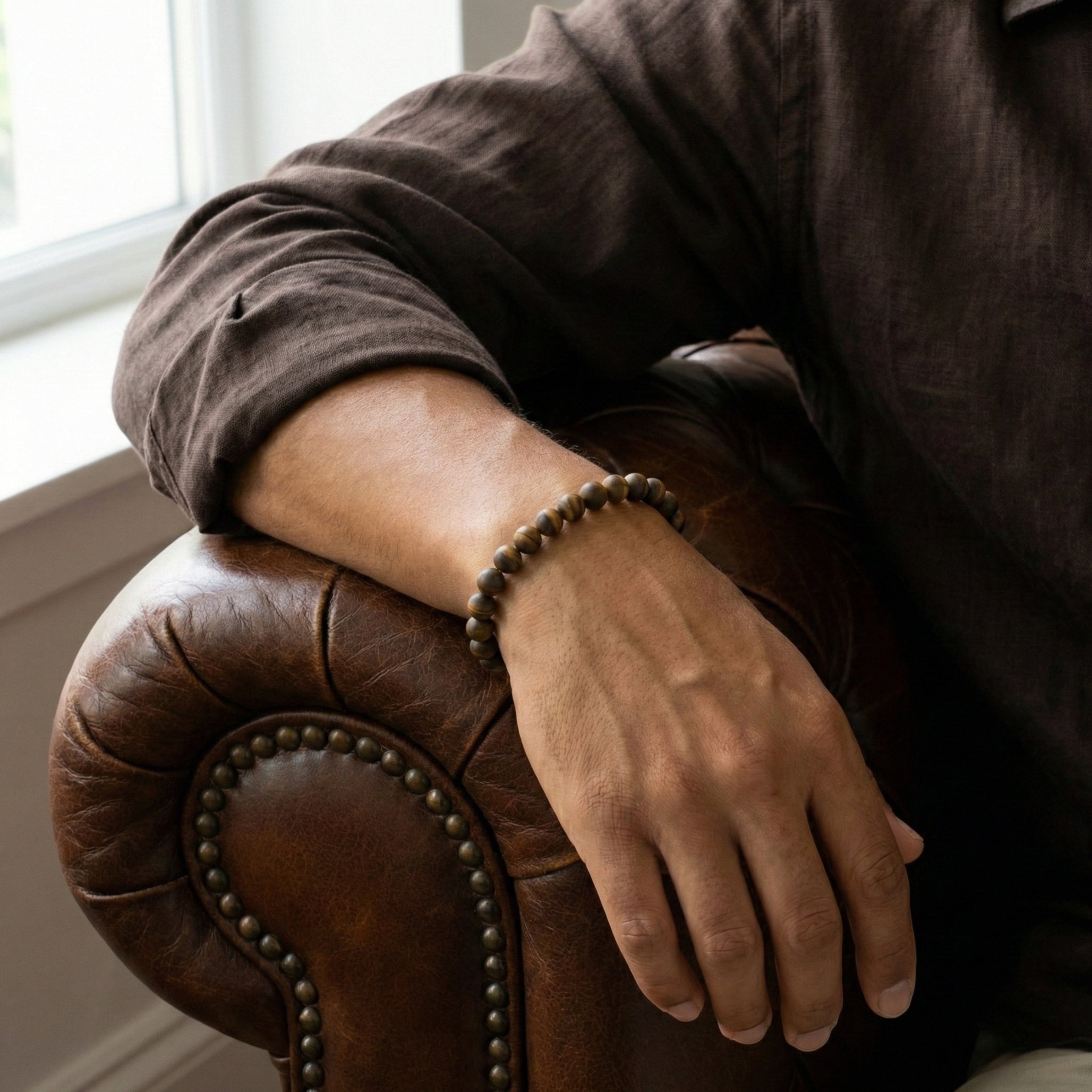 Brown tiger eye men’s bracelet with matte round natural stone beads worn on wrist in a lifestyle setting