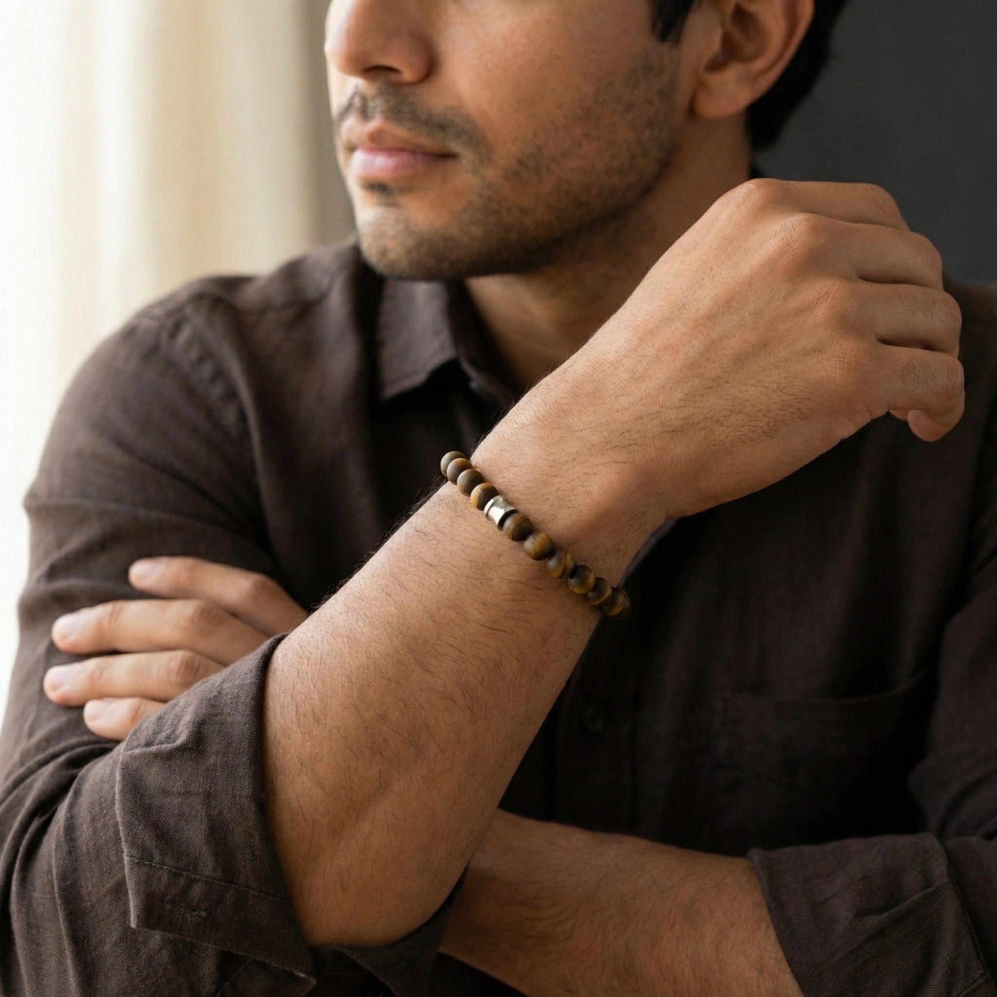 Brown tiger eye beaded men’s bracelet with matte natural stone beads and stainless steel detail worn on wrist