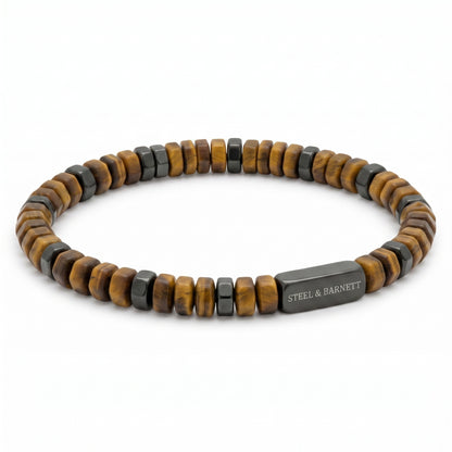 A beaded stretch bracelet featuring alternating natural tiger's eye beads and dark gray metallic square beads, with a rectangular dark gray metal clasp engraved with 'STEEL & BARNETT'.