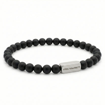 black beaded men’s bracelet with matte round beads and brushed stainless steel bar on white background