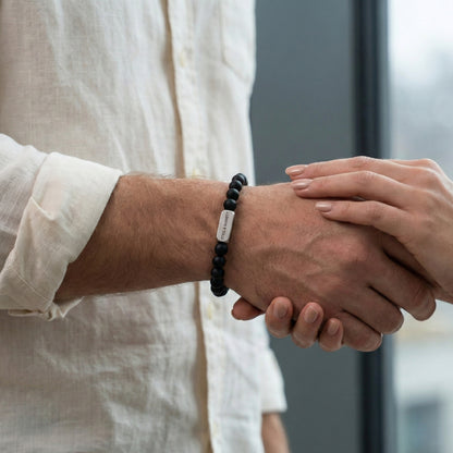 black beaded men’s bracelet with brushed stainless steel bar worn on wrist in handshake close up