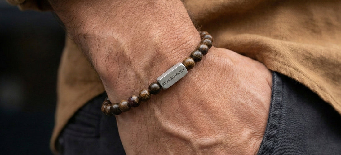 Person wearing a brown beaded bracelet with a metal tag on a blurred background