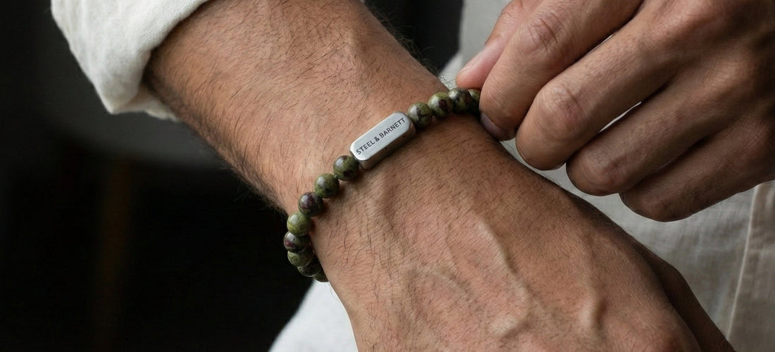 Person wearing a dragon blood jasper bracelet on a dark background