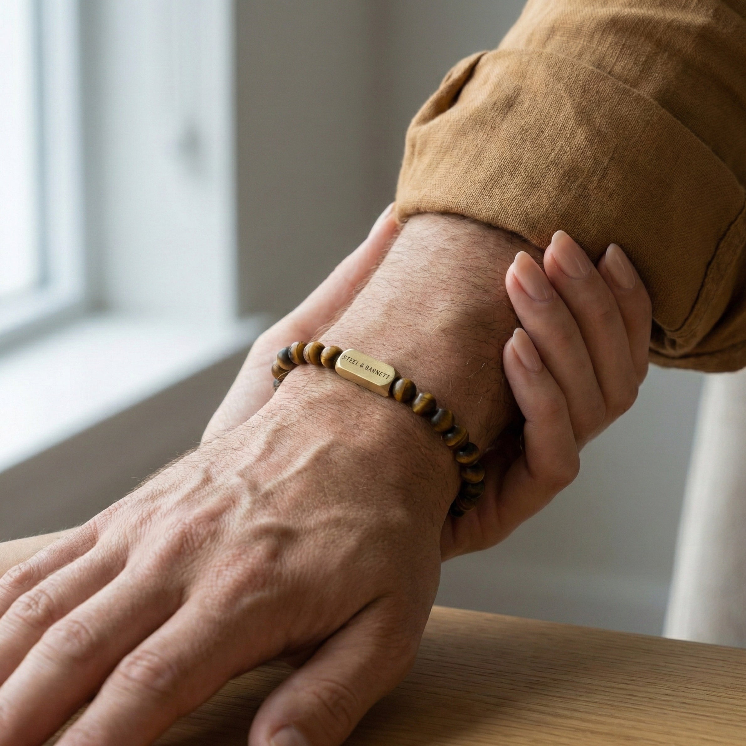 Tiger eye men’s bracelet with brown and gold stone beads and plated 18K gold clasp worn on wrist