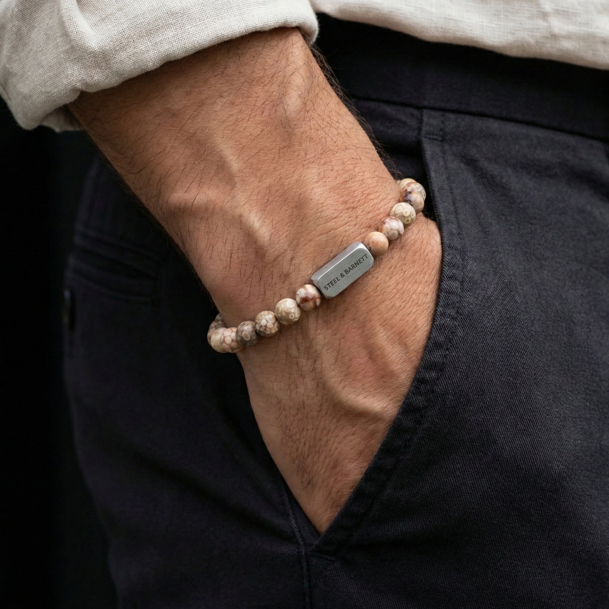 Maifanite men’s bracelet with natural stone beads and brushed stainless steel bar worn on wrist with hand in pocket
