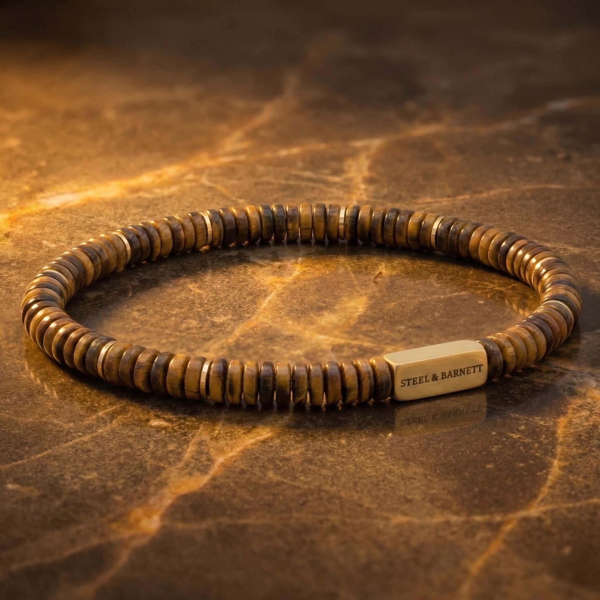 Brown tiger eye men's beaded bracelet with matte disc beads and plated 18K gold accent plate displayed on a marble surface close up detail