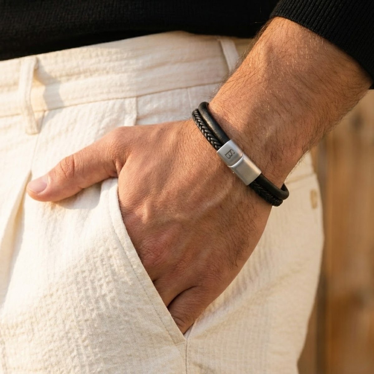 Black cowhide leather bracelet with braided detail and brushed stainless steel clasp worn on wrist 