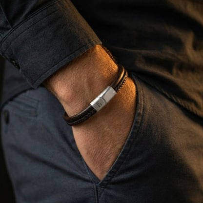 Brown braided leather men's bracelet with brushed stainless steel clasp worn on wrist with casual jacket sleeve